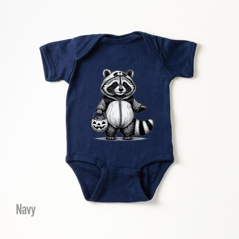 May include: A navy blue baby onesie with a black and white illustration of a raccoon dressed in a costume holding a jack-o-lantern.