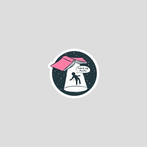 May include: A pink book with a white page open, floating in a dark blue space with white stars. A silhouette of a person is falling through the open book, with a speech bubble above them that says "Take me away".