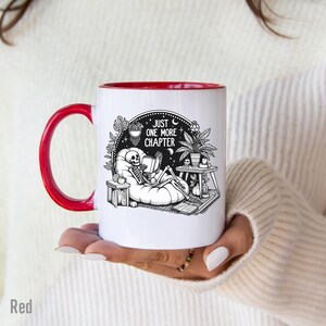 Red accent coffee mug with skeleton reading while lounging in a boho style room with the words Just One More Chapter