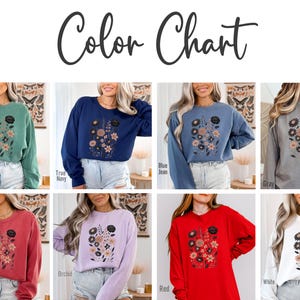 Peut inclure: Un nuancier pr&eacute;sente huit sweatshirts &agrave; col ras du cou de diff&eacute;rentes couleurs : vert clair, bleu marine, bleu jean, gris, cramoisi, orchid&eacute;e, rouge et blanc. Chaque sweat-shirt pr&eacute;sente un motif floral avec le texte "Color Chart".