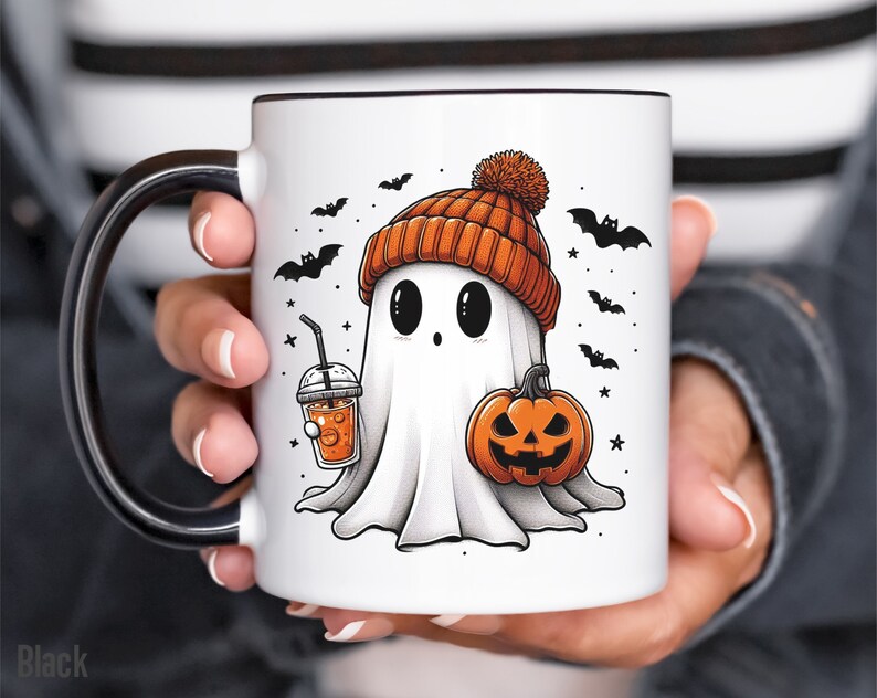 May include: White ceramic mug with a black handle. The mug features a cartoon ghost wearing an orange and brown knit hat, holding a pumpkin and a cup of orange juice. The background is white with black bats and stars.
