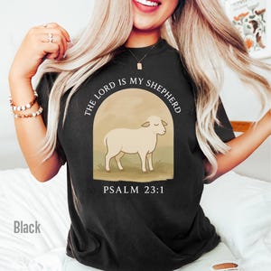 Op de afbeelding: Zwart T-shirt met een witte schaapillustratie en de tekst "The Lord is my Shepherd, Psalm 23:1".
