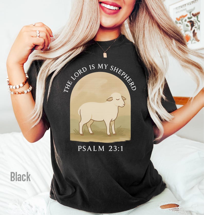 Op de afbeelding: Zwart T-shirt met een witte schaapillustratie en de tekst "The Lord is my Shepherd, Psalm 23:1".