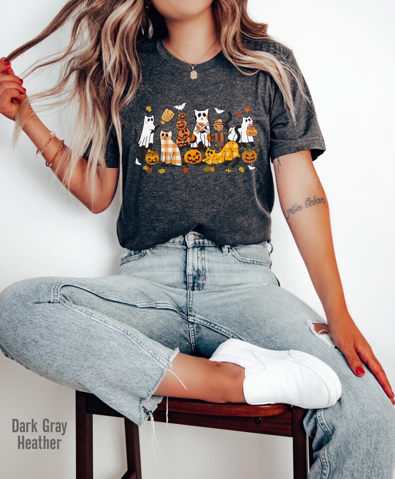 May include: Dark gray heather t-shirt featuring a Halloween-themed graphic. The design includes cartoon cats dressed as ghosts, pumpkins, and scarecrows. The text "Dark Gray Heather" is visible at the bottom left of the image.