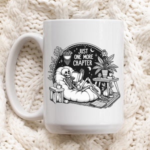 White coffee mug with skeleton reading while lounging in a boho style room with the words Just One More Chapter