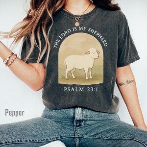 Op de afbeelding: Een antracietkleurig T-shirt met een witte afbeelding van een schaap en de tekst "The Lord is my Shepherd, Psalm 23:1".