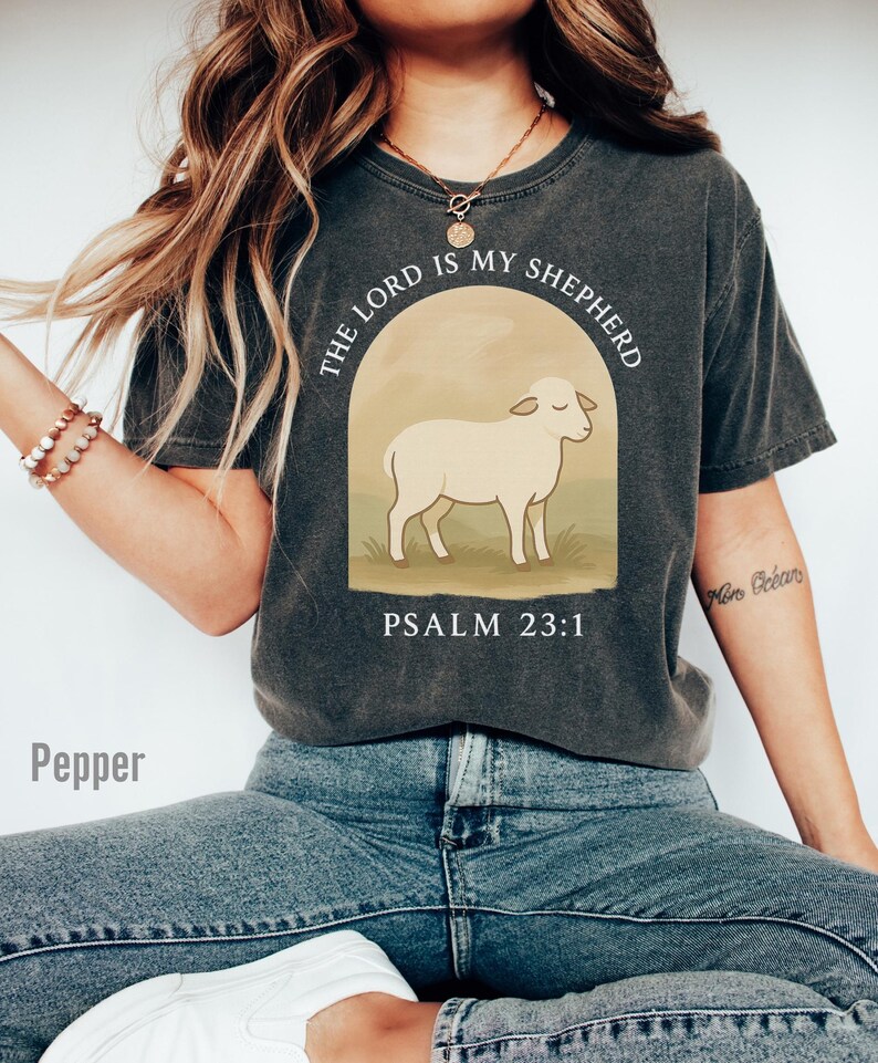 Op de afbeelding: Een antracietkleurig T-shirt met een witte afbeelding van een schaap en de tekst "The Lord is my Shepherd, Psalm 23:1".