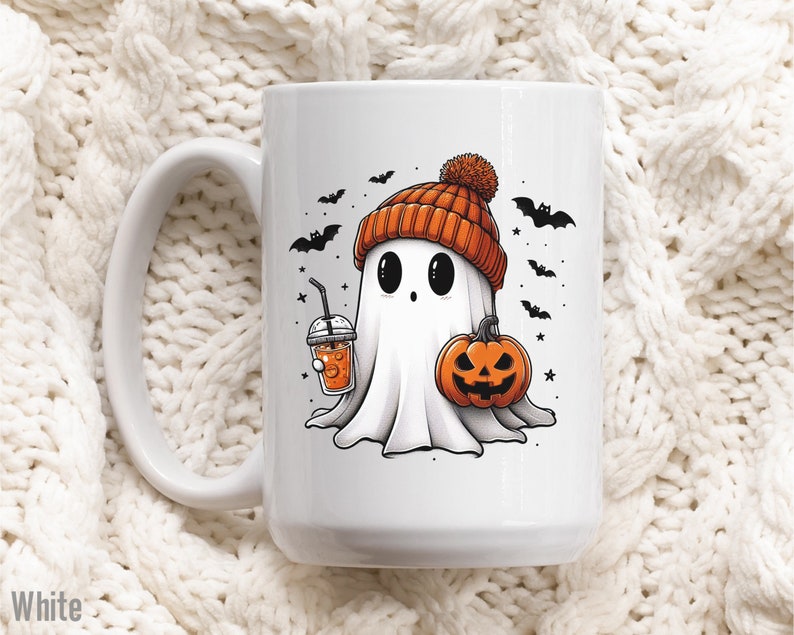 May include: White ceramic mug with a Halloween-themed design. A cartoon ghost wearing an orange and white hat holds a pumpkin and a cup of orange liquid. The ghost has large black eyes and a small mouth. Bats and stars are in the background.