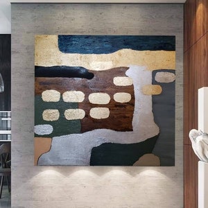 May include: Abstract painting with geometric shapes in shades of brown, green, gold, and silver. The painting is displayed on a wall in a modern home.