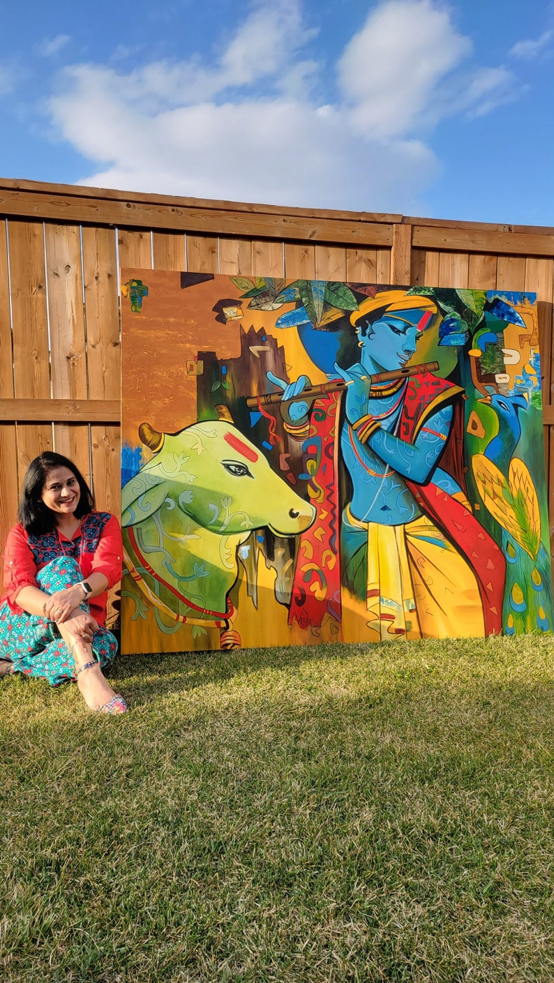 May include: A colorful painting depicting a blue figure playing a flute, a green cow, and a peacock. The painting is set against a yellow and orange background with intricate patterns.