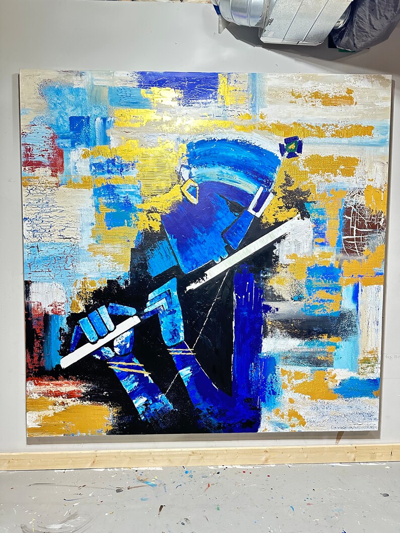 May include: Abstract painting of a person playing a flute. The painting is done in shades of blue, gold, and white. The person is depicted in a stylised way, with a large head and long, thin limbs. The flute is white and is held in the person's right hand.