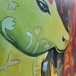 May include: A close-up of a green and yellow abstract painting with a stylized cow's head and floral designs. The cow's eye is black and the background is a mix of red, yellow, and blue.