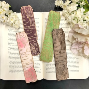 May include: Set of five wooden bookmarks featuring fairies with intricate designs and quotes about the world of weeping. The bookmarks are painted in shades of green, pink, brown, and purple.