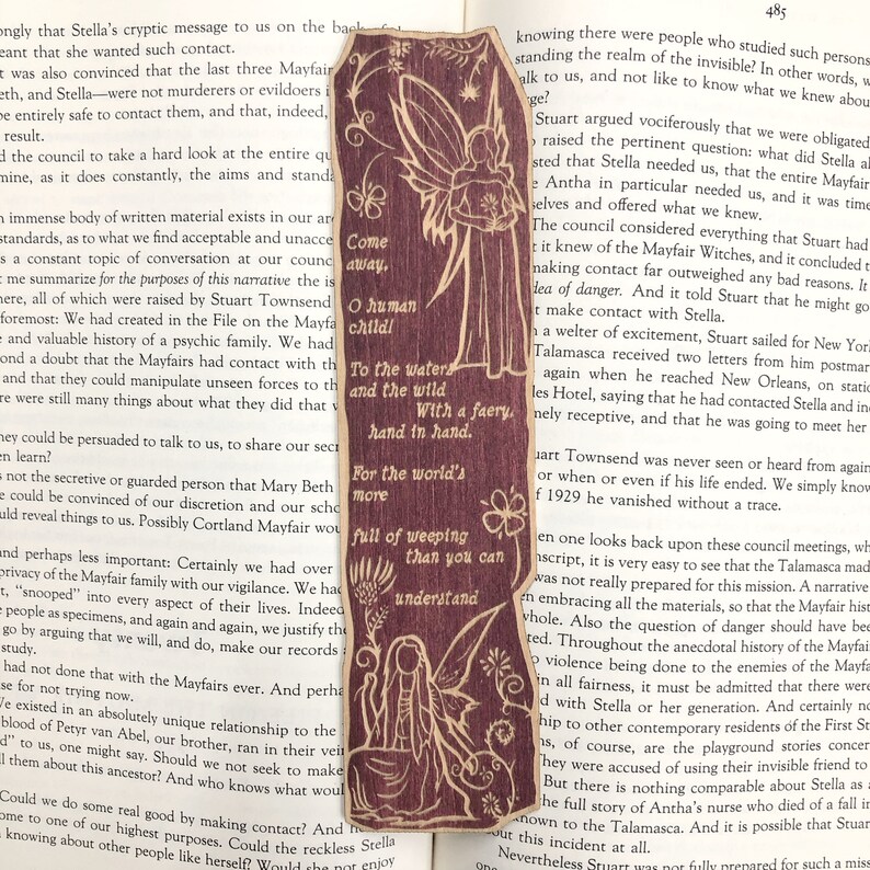 May include: A brown and tan bookmark with a fairy illustration. The fairy is holding a flower and has a quote that reads "Come away, O human child! To the waters and the wild. With a faery, hand in hand. For the world's more full of weeping than you can understand."