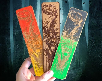 Può includere: Tre segnalibri in legno a tema Halloween. I segnalibri raffigurano una strega, una zucca e un teschio. I segnalibri sono dipinti in tonalità di verde, arancione e nero.