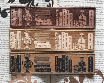 May include: Three wooden bookmarks with a vintage aesthetic. Each bookmark features a different design with a stack of books, a bottle of liquor, and a glass. The text on the bookmarks reads "The Secret History", "Black Chalk", "The Lake", "Dead Languages", "Truly Devious", "The Dead Poet's Society", "The Truants", "The Goldfinch", "Hangsaman", and "Ninth House".