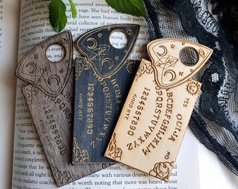 Peut inclure: Trois planches de Ouija en bois avec des lettres noires et blanches. Les planches sont en forme de larme avec un trou en haut. Les planches ont les lettres de l'alphabet, les chiffres et les mots "oui", "non" et "au revoir" imprimés dessus.