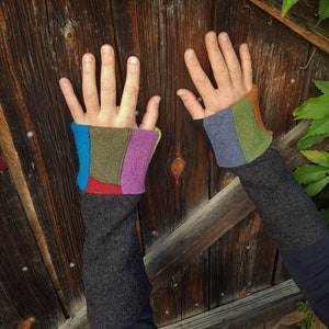 Könnte beinhalten: Ein Paar schwarze Fingerlose Handschuhe mit bunten Patchwork-Stoff am Handgelenk. Die Handschuhe sind aus einem weichen, flauschigen Material.