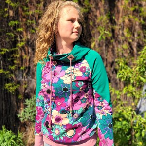 May include: A teal and pink hooded sweatshirt with a floral print. The hoodie has a cowl neck and a drawstring.