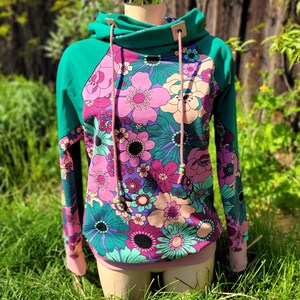 May include: A teal green and pink floral print hoodie with a drawstring hood and a pink and teal color block design.