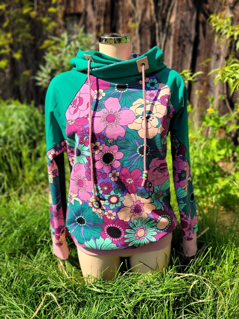 May include: A teal green and pink floral print hoodie with a drawstring hood and a pink and teal color block design.