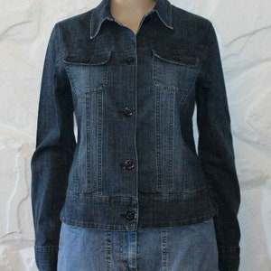 Puede incluir: Una chaqueta vaquera azul con cierre de botones y dos bolsillos de solapa en el pecho. La chaqueta tiene una silueta ligeramente entallada y está hecha de una tela vaquera suave y cómoda.