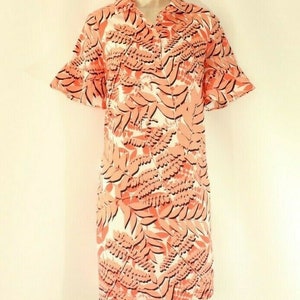 May include: A white dress with a pink and black floral print. The dress has a collared neckline, short sleeves, and a relaxed fit.