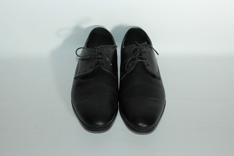 May include: A pair of black leather lace-up shoes with a textured pattern.