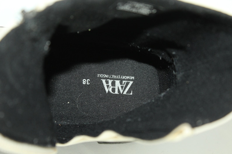 May include: Close-up of the inside of a black shoe with a white insole. The insole has the text "ZARA" and "MEMORY EFFECT INSOLE" printed on it. The shoe size is 38.