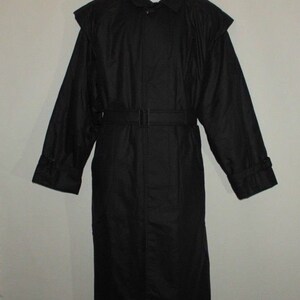 以下が含まれることがあります： ベルトと襟が付いた黒い長袖のコート。コートは肩にケープのようなディテールが施されたユニークなデザインです。