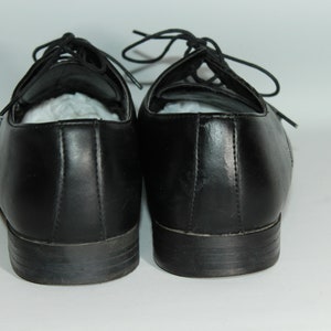 May include: A pair of black leather lace-up shoes. The shoes have a simple design and are in good condition.