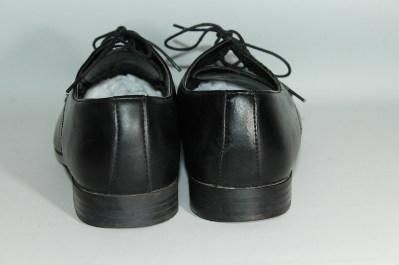 May include: A pair of black leather lace-up shoes. The shoes have a simple design and are in good condition.