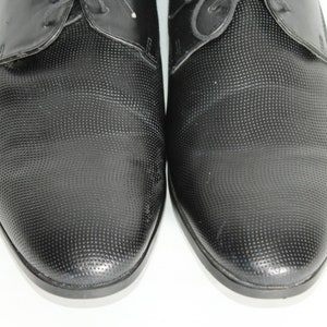 May include: A pair of black leather dress shoes with a textured pattern. The shoes have a lace-up closure and a pointed toe.