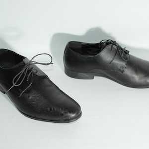 May include: A pair of black leather lace-up shoes with a textured pattern.