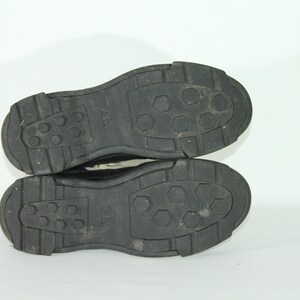 May include: Close-up of the black soles of a pair of shoes. The soles have a textured pattern with hexagonal shapes and the word "ZARA" is visible on the soles.