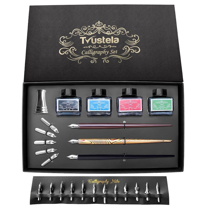 May include: A black calligraphy set with the text "Tvustela Calligraphy Set" on the box lid. The set includes ink bottles, pens, nibs, and a pen holder. The ink bottles are labeled with the colors black, blue, red, and green.