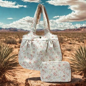 Pode incluir: Um conjunto de sacola e bolsa de cosméticos combinando com estampa floral. As bolsas apresentam um fundo claro com um padrão de flores rosa e verde. A sacola tem um fecho de botão e uma alça.