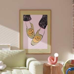 以下が含まれることがあります： 黄色い笑顔のついた緑色の靴のペアを描いた額縁付きのイラスト。靴は、黒とピンクの花柄のピンク色の背景の上にあります。
