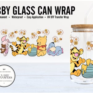 May include: A clear glass can with a wooden lid and a straw. The can is decorated with a Winnie the Pooh themed design featuring Winnie the Pooh, Tigger, Piglet, and Eeyore. The design also includes honey pots and yellow flowers.
