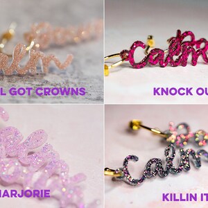 May include: Four pairs of gold hoop earrings with the word "calm" written in sparkly script. The earrings are in four different colors: pink, red, purple, and gray. The text below each pair of earrings reads: "We all got crowns", "Knock out", "Marjorie", and "Killin it".