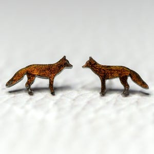 May include: A pair of fox-shaped earrings made of metal with a brown, metallic finish.
