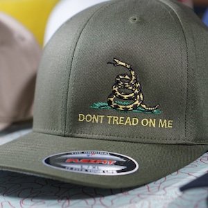 May include: A green baseball cap with a yellow embroidered snake and the text "Don't Tread On Me".