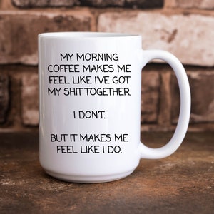 Puede incluir: Taza de café de cerámica blanca con texto negro que dice "My morning coffee makes me feel like I've got my shit together. I don't. But it makes me feel like I do."