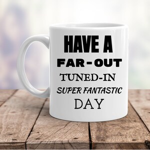 May include: White ceramic coffee mug with black text that reads "Have a Far-Out Tuned-In Super Fantastic Day."
