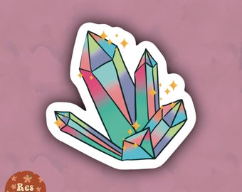 Könnte beinhalten: Ein Aufkleber mit einer Gruppe farbenfroher Kristalle mit einem Regenbogenverlauf aus Rosa, Blau, Grün und Gelb. Die Kristalle sind schwarz umrandet und haben goldene Sternakzente. Der Aufkleber hat einen weißen Rand auf einem malvenfarbenen Hintergrund.