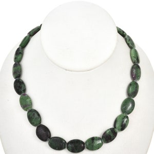 May include: A green and pink oval-shaped gemstone necklace. The necklace is made of natural stones and is strung on a silver chain.