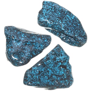 May include: Three irregularly shaped turquoise stones with a black matrix. The stones have a smooth, polished surface and a blue-green color.