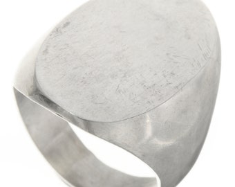 May include: A silver signet ring with a smooth, oval-shaped top. The ring is made of metal and has a polished finish.