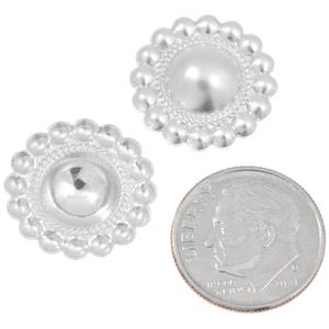 May include: Two silver metal buttons with a circular design. Each button features a central raised disc and a beaded border. A coin is included for size comparison. The buttons are small in size.