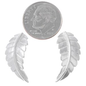 May include: A pair of silver earrings shaped like leaves. The earrings are about the size of a dime.